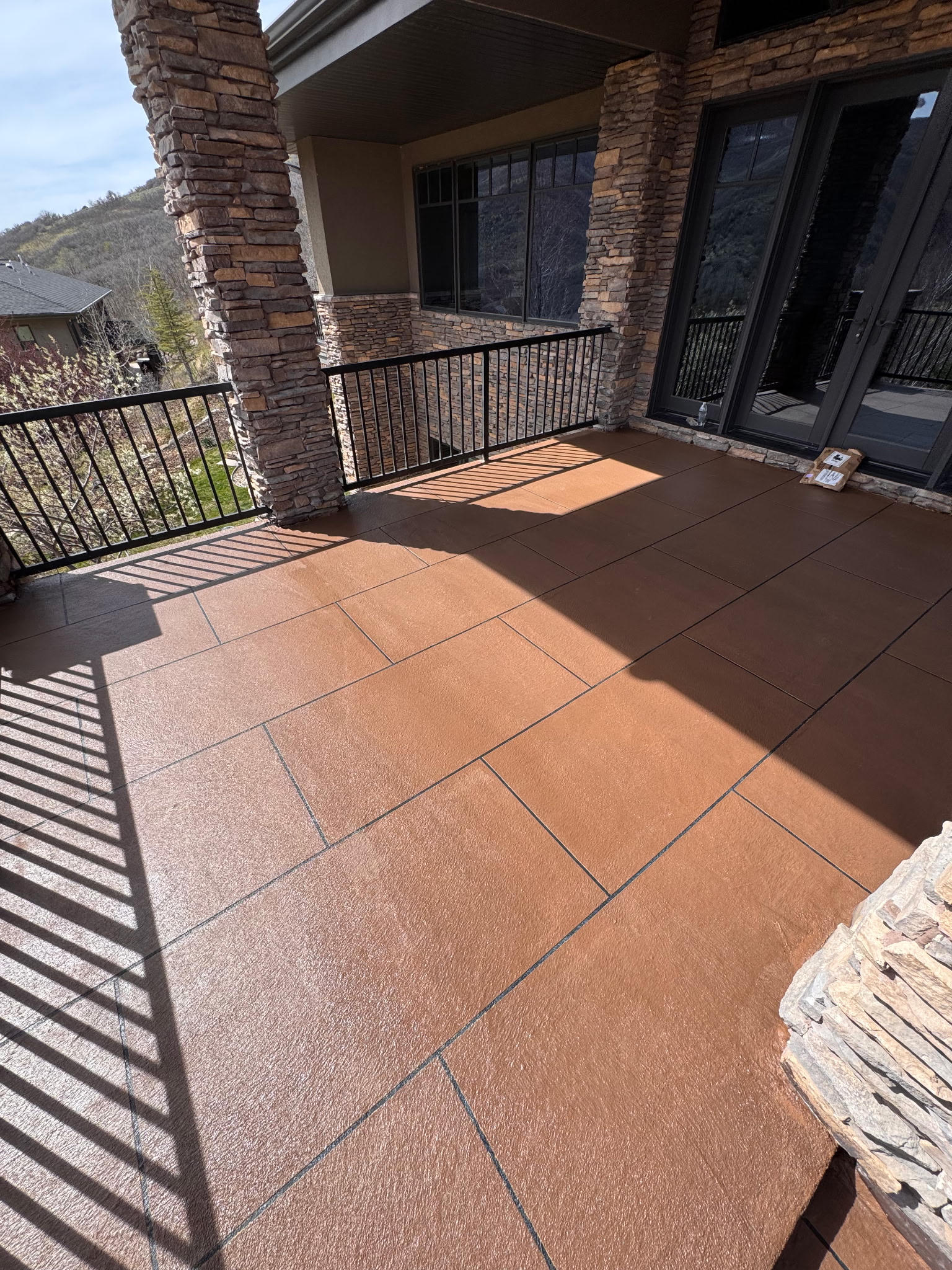 Sunlit outdoor patio with terracotta tiles and stone pillars.