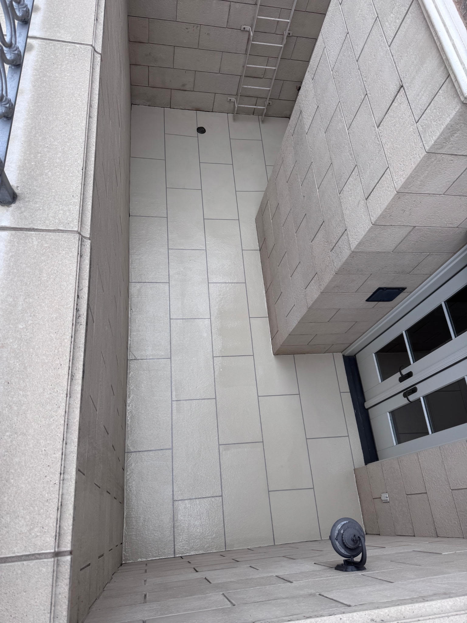 A clean, tiled balcony with a glass door and window.