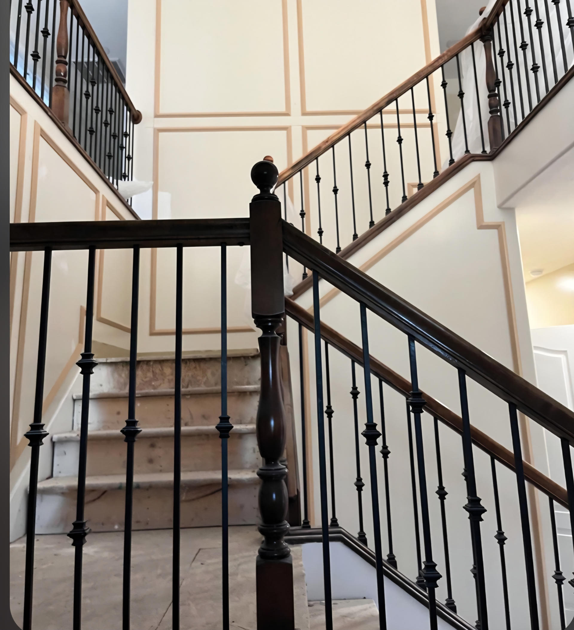 Elegant staircase with black wrought iron railing and wooden handrail.