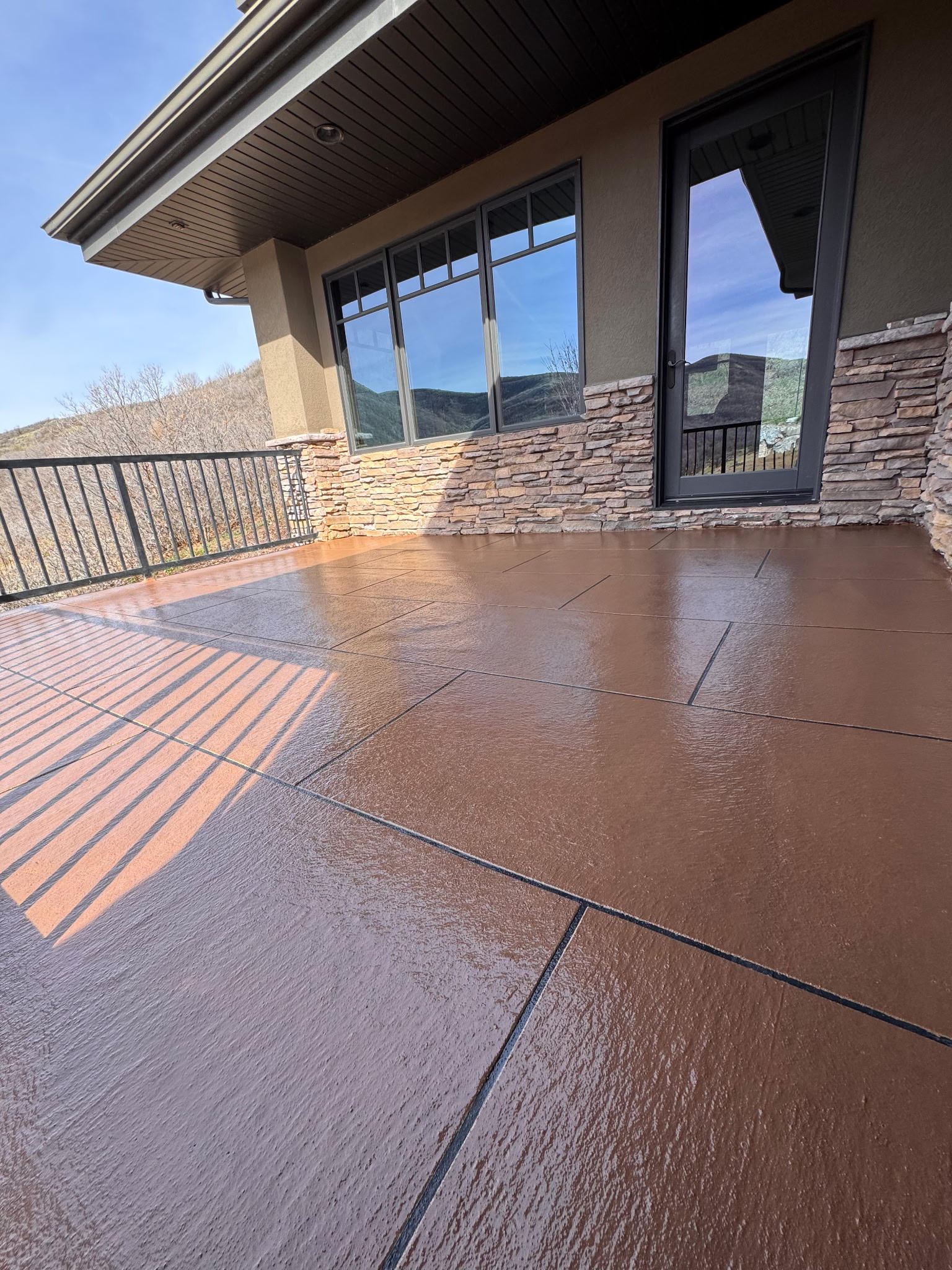 Sunlit outdoor patio with textured concrete floor and modern railing.