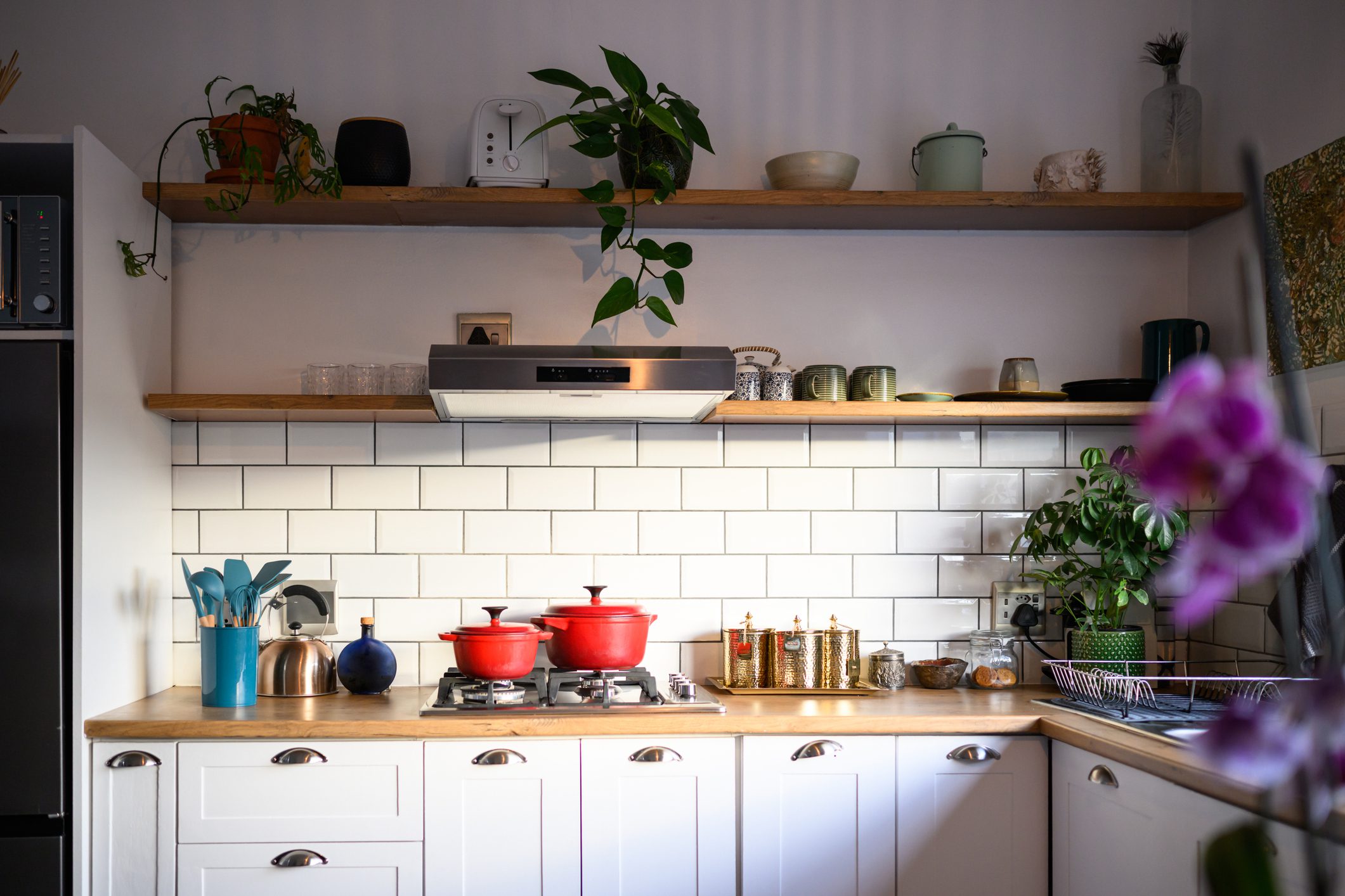 Cozy kitchen with red pots and white subway tiles.