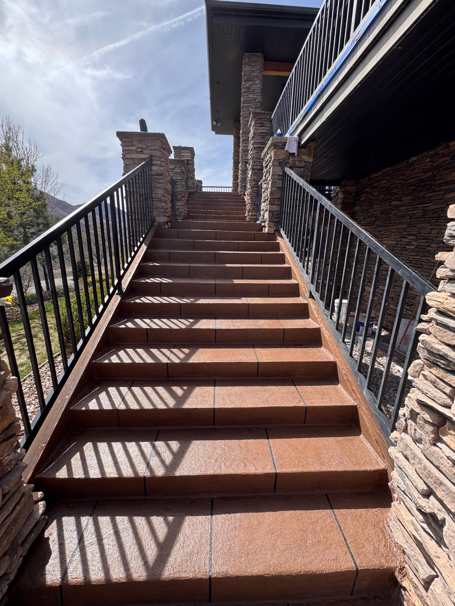 Sunlit outdoor stairs with metal railings casting shadows.